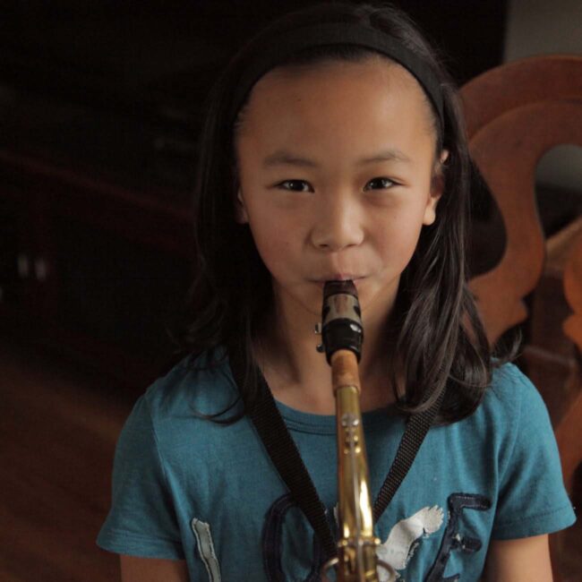 Young girl playing a saxophone.